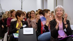 Teilnehmende sitzen im Saal und klatschen