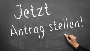 Auf einer Tafel steht mit Kreide geschrieben "Jetzt Antrag stellen!".