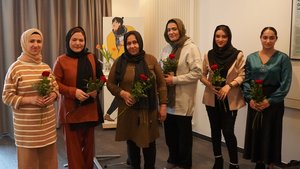 Sieben Frauen stehen nebeneinander, halten eine Rose in der Hand und schauen in die Kamera