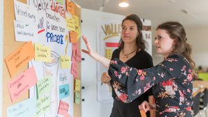 Zwei Frauen stehen vor eine Pinwand