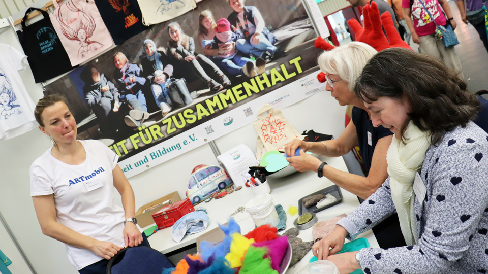 Drei Frauen basteln an einem Messestand