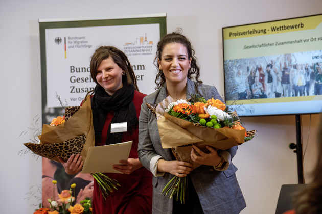 Zwei Frauen halten einen Blumenstrauß in der Hand.