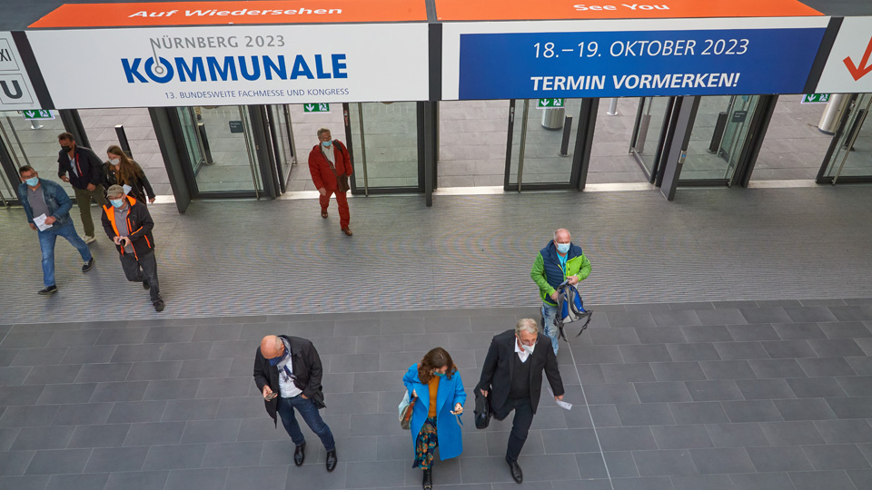 Menschen laufen durch Eingangstore einer Messe