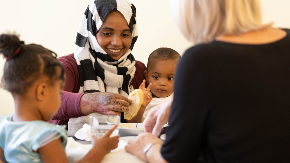 Zwei Frauen und zwei Kinder sitzen beim Frühstück